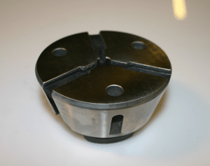 En närbild av en metallchuck med tre käftar som används för att säkra föremål under bearbetning.