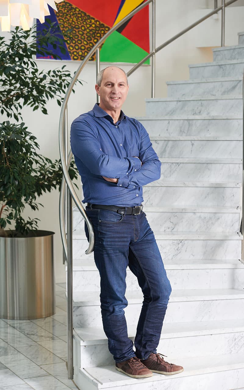 En man i blå skjorta och jeans står vid en marmortrappa